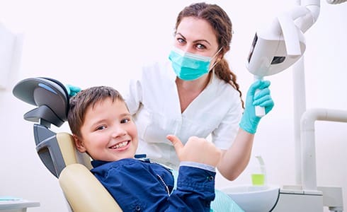 Child giving thumbs up after pulp therapy