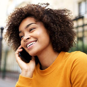 Woman smiling while talking on phone outside