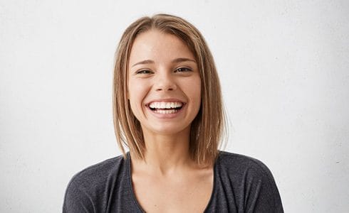 young woman in black shirt smiling against white background 
