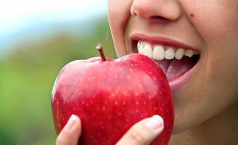 close up of person eating red apple 