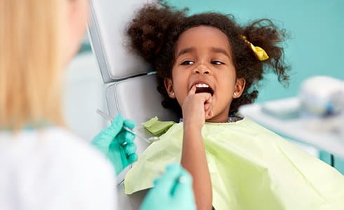 Child pointing to smile after tooth-colored filling