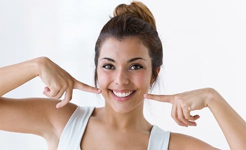 Woman pointing to smile after teeth whitening
