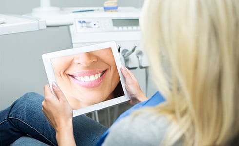 Woman looking at virtual smile design on tablet computer