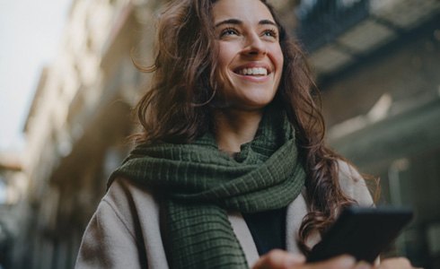 Alt image tag: woman smiling and holding her phone 