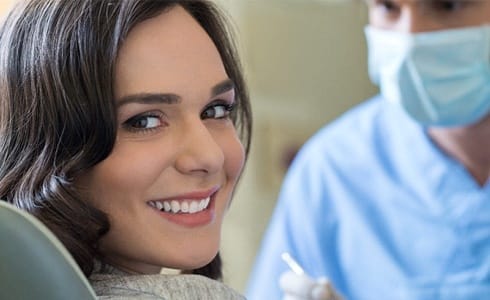 A young woman seated in the dentist’s chair preparing to receive preventive treatment to improve her smile