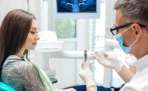 dentist showing a patient a dental implant model