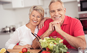 Smiling couple sitting in front of healthy foods