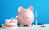 Piggy bank and dental tools representing the cost of dental emergencies in Oklahoma City
