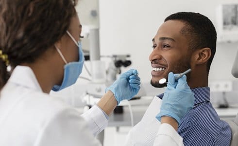 man sitting in dental chair and smiling at his dentist 