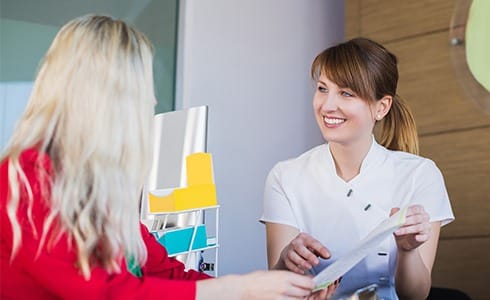 Dental team member handing patient a dental insurance form