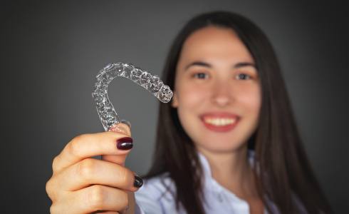 Woman holding up Invisalign tray