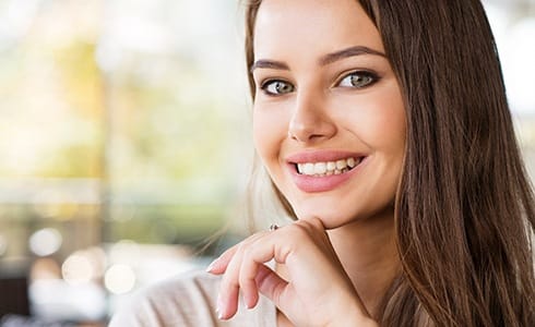 A young female with dark hair shows off her smile after receiving metal-free dental crowns in Oklahoma City