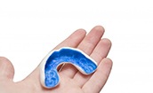 person holding a blue mouthguard in their hand