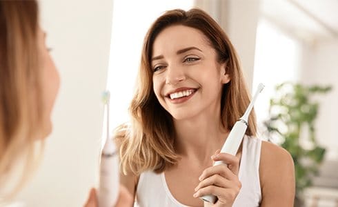 Woman brushing teeth with electric toothbrush