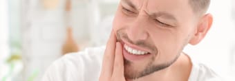 Man in need of emergency dentistry holding cheek