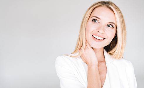 A young woman with blonde hair and wearing a white blazer smiling after receiving veneers in Oklahoma City