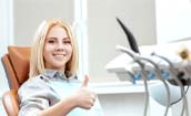 Woman smiling in dental chair with her thumb up