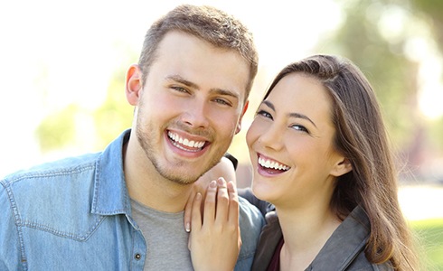 Younger couple smiling together outside