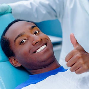 Man smiling in dental chair giving thumbs up 