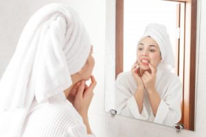 woman looking at teeth in mirror 