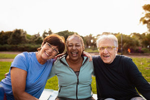 Three people sitting and smiling outside during the summer