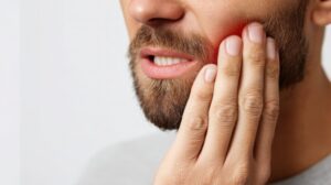 Man holding jaw in pain from denture sore.